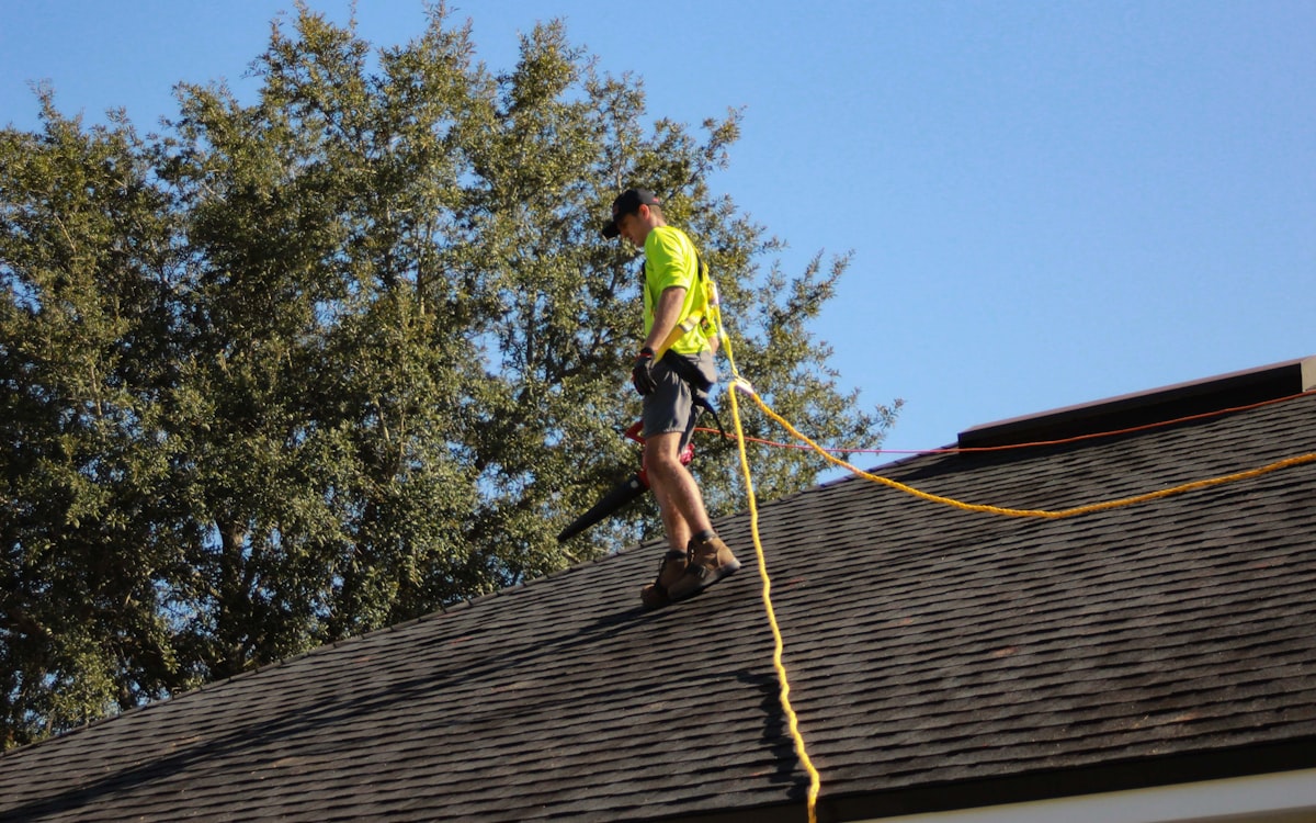 Roofer working safely on an asphalt shingle roof